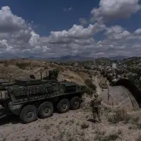 A man is halted climbing the US-Mexico border wall. Under new Trump rules, US troops sound the alarm